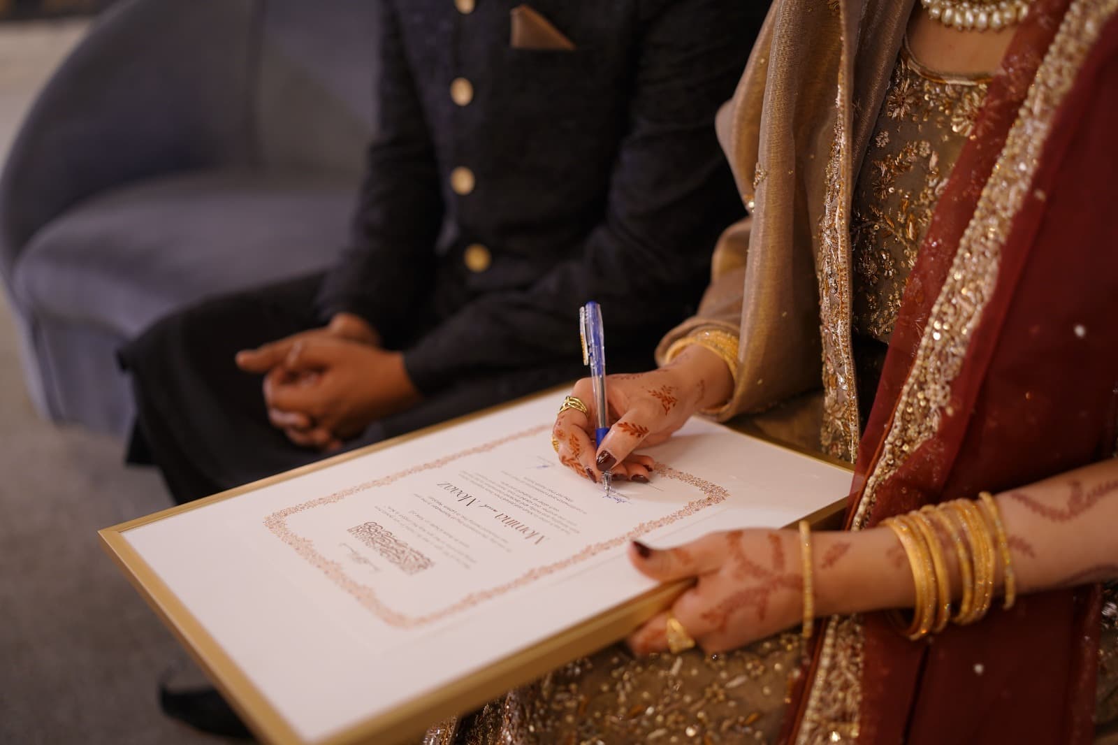 A bride in traditional dress signing her personalized nikah certificate