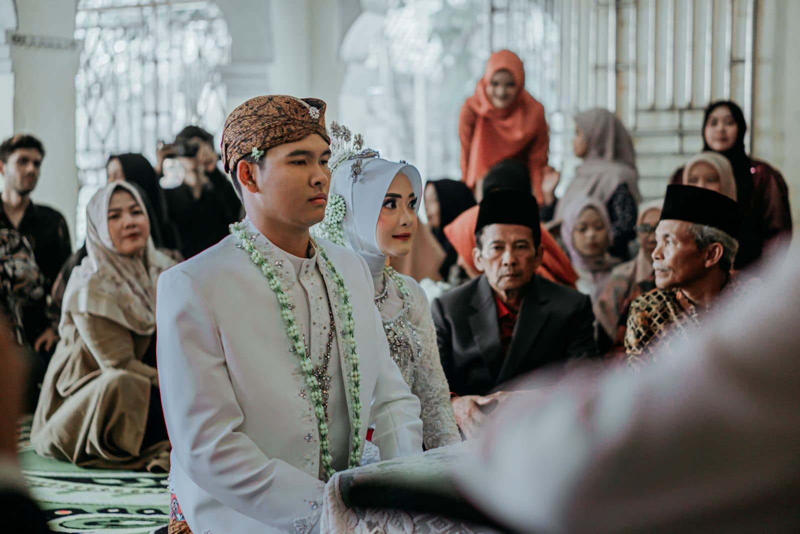 A bride and groom seated with their families during a nikah ceremony at a mosque