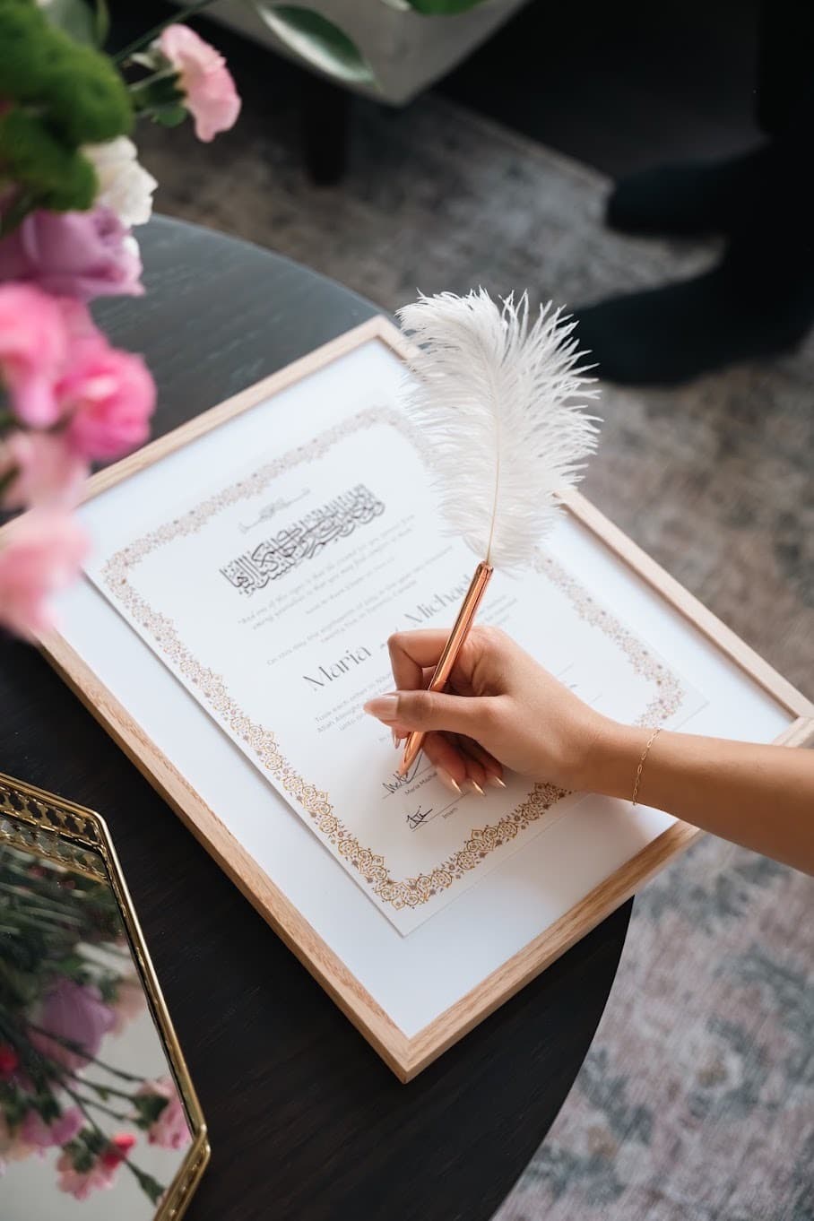 A framed custom nikah certificate with a gold ornamental border being signed
